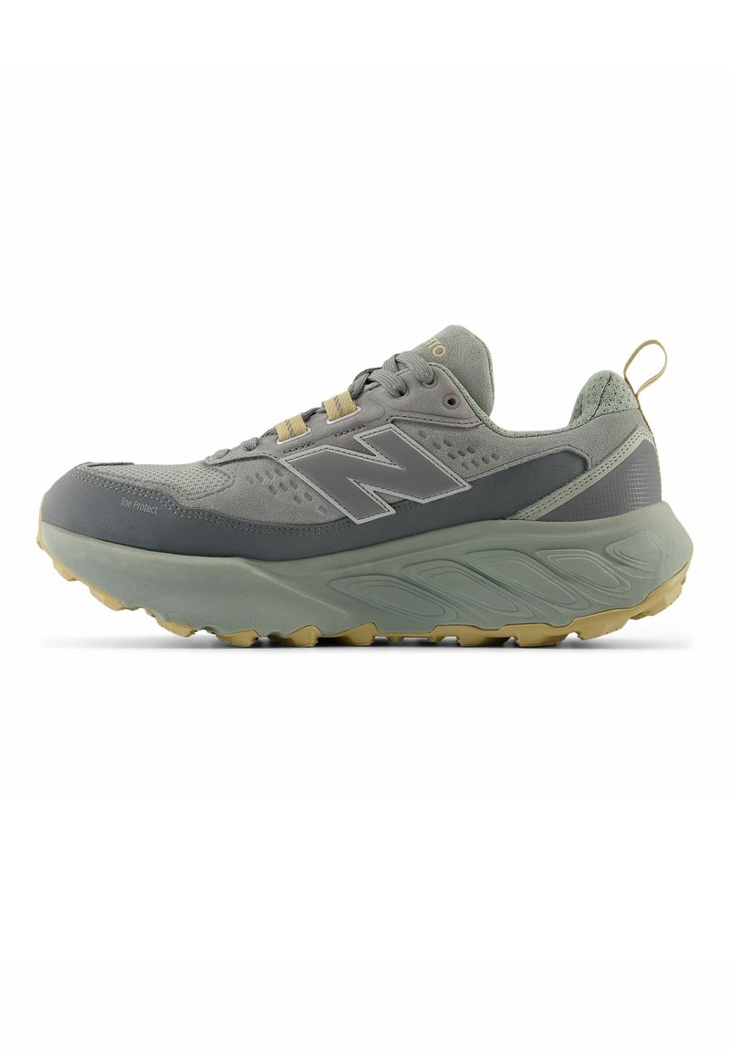Chaussure de sport New Balance grise et beige avec une semelle épaisse, un lacet à l'avant, une languette au talon et un logo sur le côté.