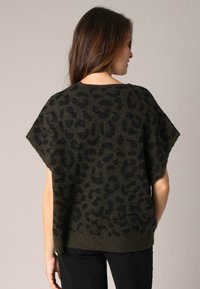 Pull en tricot vert foncé avec imprimé léopard noir, à manches courtes et à coupe décontractée, fabriqué dans un matériau doux et texturé.