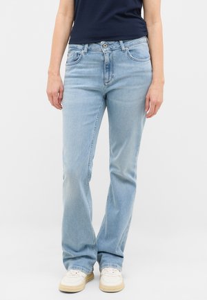 Jean en denim bleu clair avec une coupe droite, un design à cinq poches et une décoloration subtile. Porté avec des baskets blanches.