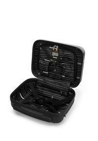 Zwarte harde koffer met ritsluiting. Binnenin beschikt hij over een gestreepte voering, meerdere vakken en banden voor veilige packing.