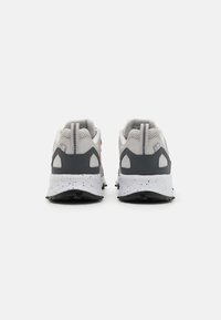 Baskets de sport grises et blanches avec un dessus en maille, un col rembourré, des accents contrastants et une semelle en caoutchouc texturée.