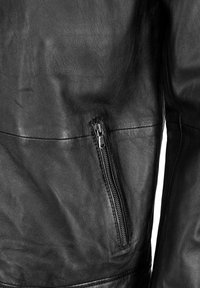 Svart läderjacka med detaljer som en dragkedjeficka, texturerad yta och en slät finish med väldefinierade sömmar.