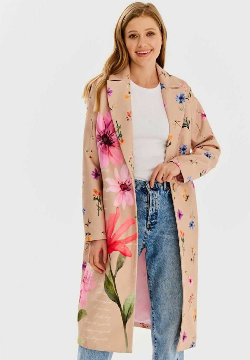 Béžový kabát s kvetinovým vzorom a dlhými rukávmi, zdobený živými ružovými, modrými a zelenými kvetmi. Mäkkučký materiál a otvorený predný dizajn.