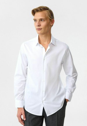 Witte lange mouwen knoopshirt met een klassieke kraag, rechte zoom en een gladde textuur, gedragen met gemusterde grijze broek.