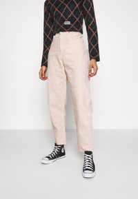 Pantalones de talle alto en pink pálido hechos de algodón, con un corte holgado y piernas rectas, combinados con zapatillas altas negras.
