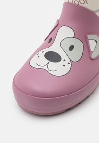 Sabots en caoutchouc rose avec un design de visage de chien, présentant de grands yeux et un museau texturé, un bout arrondi et des accents surélevés sur les côtés.