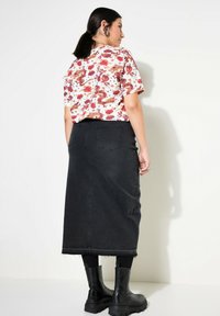 Wit met bloemenpatroon korte mouwen shirt gecombineerd met een zwarte denim maxi rok en zwarte enkellaarzen, met twee achterzakken.