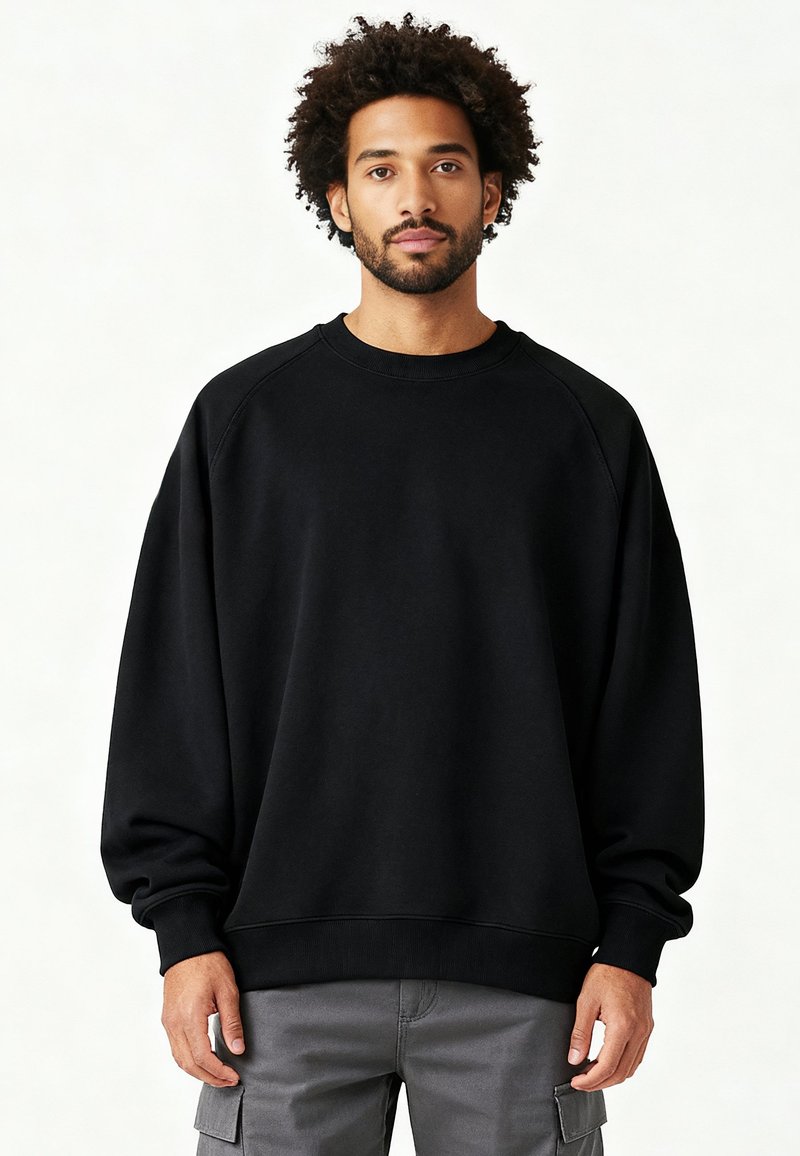 Felpa nera con maniche raglan, polsini a coste e scollo rotondo. Realizzata in morbido tessuto, con vestibilità morbida.