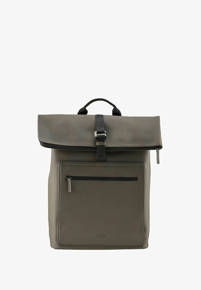 Mochila gris mate con solapa superior sujeta por una correa negra y un cinturón, bolsillo frontal con cremallera y una pequeña asa en la parte superior.