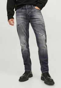 Grå denimjeans med slitna detaljer, rak passform, femficksdesign, kombinerat med svarta snörstövlar för en robust look.