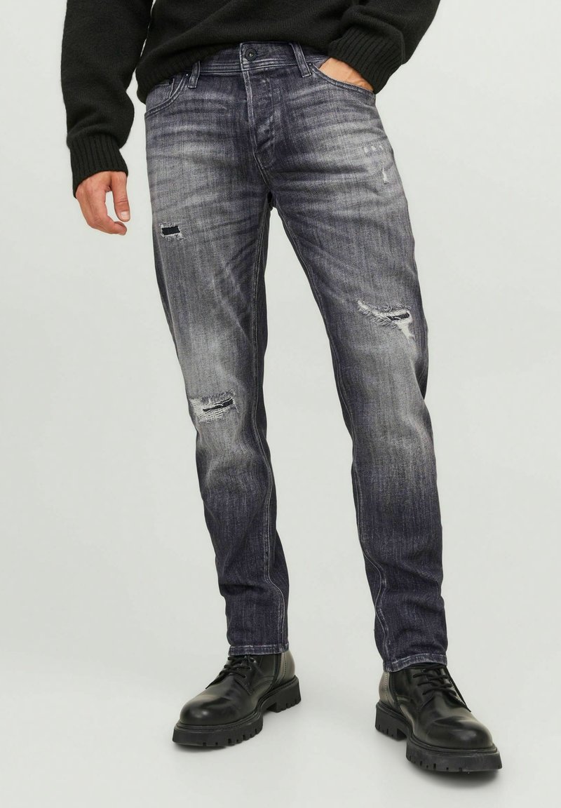 Grå denimjeans med slitna detaljer, rak passform, femficksdesign, kombinerat med svarta snörstövlar för en robust look.