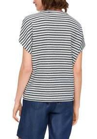 Korte mouwen top in een crèmekleurig en marineblauw gestreept patroon, met een losse pasvorm en zachte textuur, weergegeven vanaf de achterkant met denim shorts.