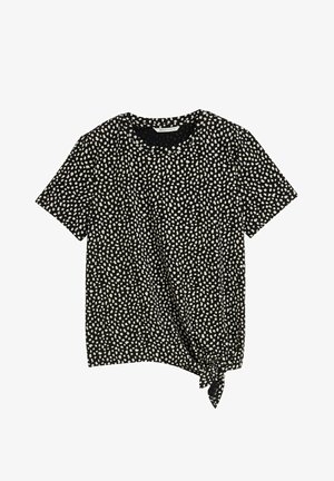 Czarna koszula z krótkim rękawem w białą plamiastą wzór. Posiada wiązanie na dolnym lewym boku jako dodatkowy element designu.