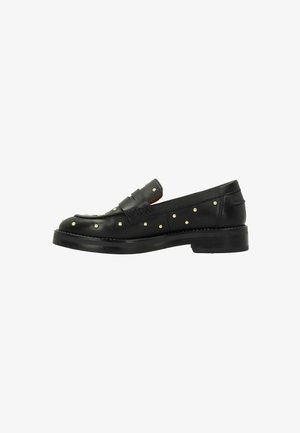 Mocassins en cuir noir avec des accents cloutés, présentant un talon bas et un design tissé sur le dessus, une texture lisse et un bout rond.