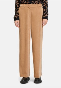 Beige corduroy wijde broekspijpen met verticale ribbels, een hoge taille en zijzakken. Gecombineerd met zwarte enkellaarsjes met een dikke zool.