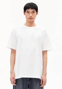 T-shirt en coton blanc oversized avec un col rond et des manches courtes. Texture lisse, tissu léger et ourlet droit.