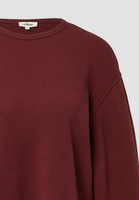 Felpa crewneck color bordeaux con collo a costine e cucitura sulla spalla visibile, caratterizzata da un piccolo etichetta bianca del marchio all'interno del collo.