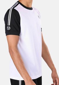 Hvit treningst-skjorte med svarte korte ermer, rund hals, med to hvite striper langs skuldrene og en logo på venstre erme.