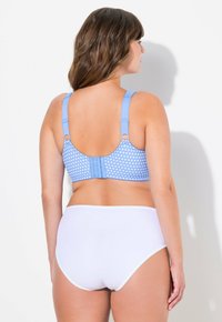 Modrý podprsenkový top s puntíky a nastavitelnými ramínky, s háčkovým zapínáním na zadní straně a hladkými bílými vysokými kalhotkami.