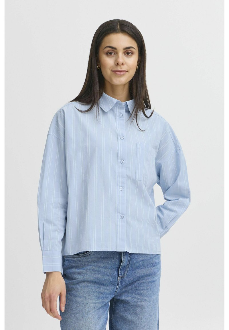 Světle modrá košile na knoflíky s vertikálními bílými pruhy, límcem, dlouhými rukávy a náprsní kapsou. Vyrobena z hladkého materiálu.