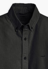 Schwarzes Hemd mit Knopfleiste und lockerem Kragen, gefertigt aus strukturiertem Stoff. Mit schwarzen Knöpfen und einem kleinen, auf der Brust gestickten Logo.