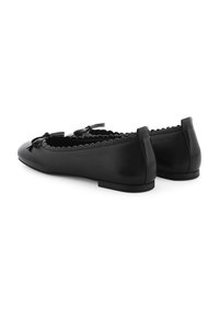 Schwarze Leder-Ballerinas mit runder Zehenpartie, gewelltem Besatz und Schleifchen vorne. Flache Sohle mit niedrigem Absatz.