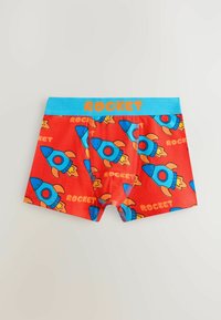Caleçons rouges pour garçons avec un motif de fusées bleu et orange, et une ceinture bleue ornée du mot "ROCKET" en lettres orange.