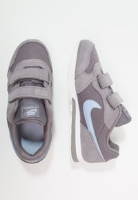 Grå träningsskor med kardborreband, i mocka och meshmaterial, ljusblå accenter, rund tå och en vit gummisula.