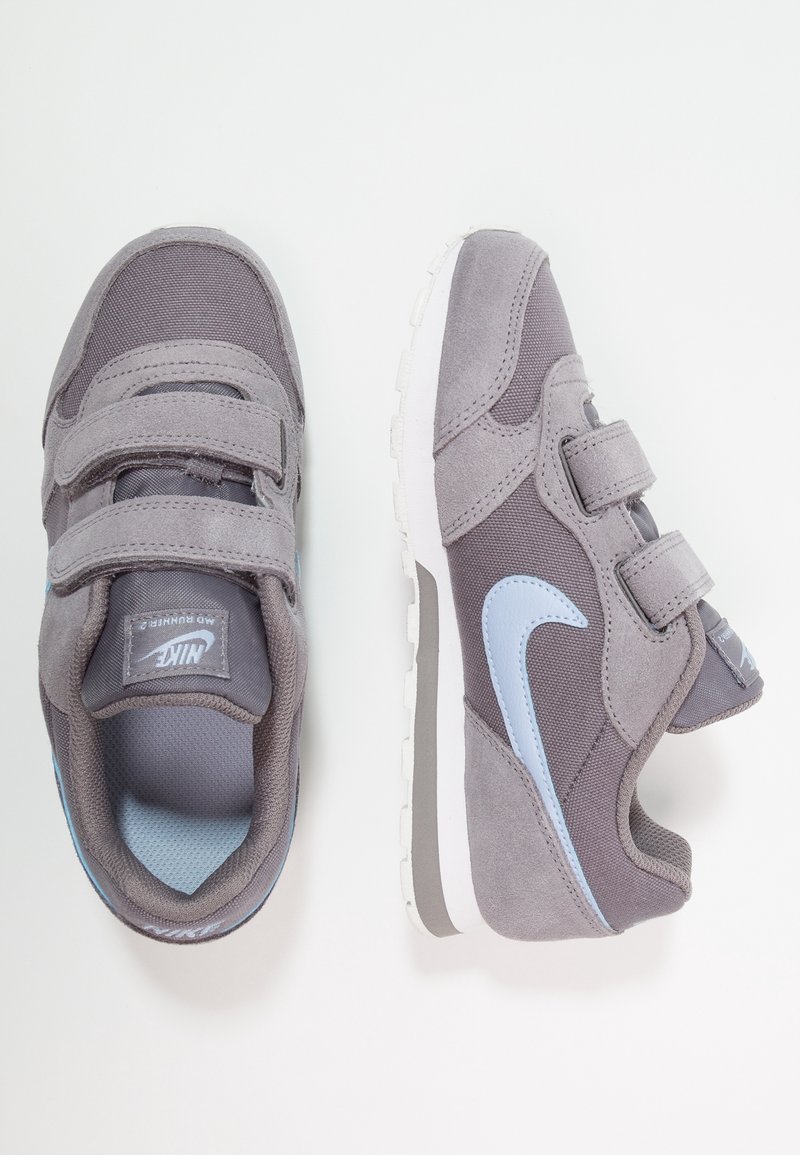Grå träningsskor med kardborreband, i mocka och meshmaterial, ljusblå accenter, rund tå och en vit gummisula.