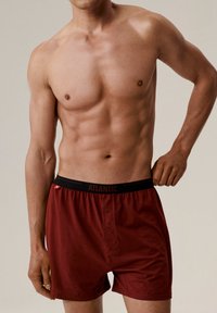 Czerwone bawełniane bokserki z czarnym elastycznym pasem z logo "ATLANTIC", z przodu z zapięciem na guzik oraz gładką fakturą.