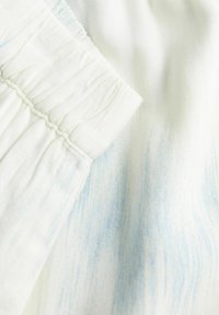 Baltas audinys su subtiliais mėlynais dryžiais, su susiraukšlėjusiu elastingu juosmeniu ir švelniu tekstūra. Detalus artimas medžiagos vaizdas.