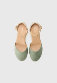 Grønne semskede slingback-sko med en beige snøredetalje og justerbar ankelrem. Rund tå-design med en glat læderforing.