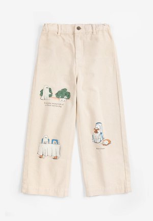 Pantalon beige avec des illustrations d’un fantôme et d’un chien dans différentes scènes, y compris assis, en train de lire et cachés derrière une table.