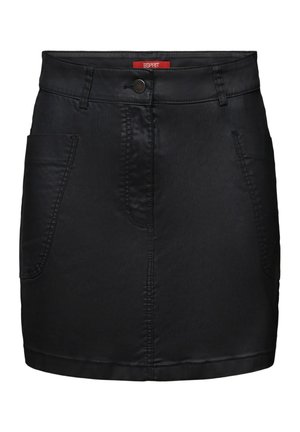 Kvinde iført hvid langærmet top, sort nederdel, bordeauxrøde og grå sokker, sorte loafers, holder en pinktaske-rem over skulderen.