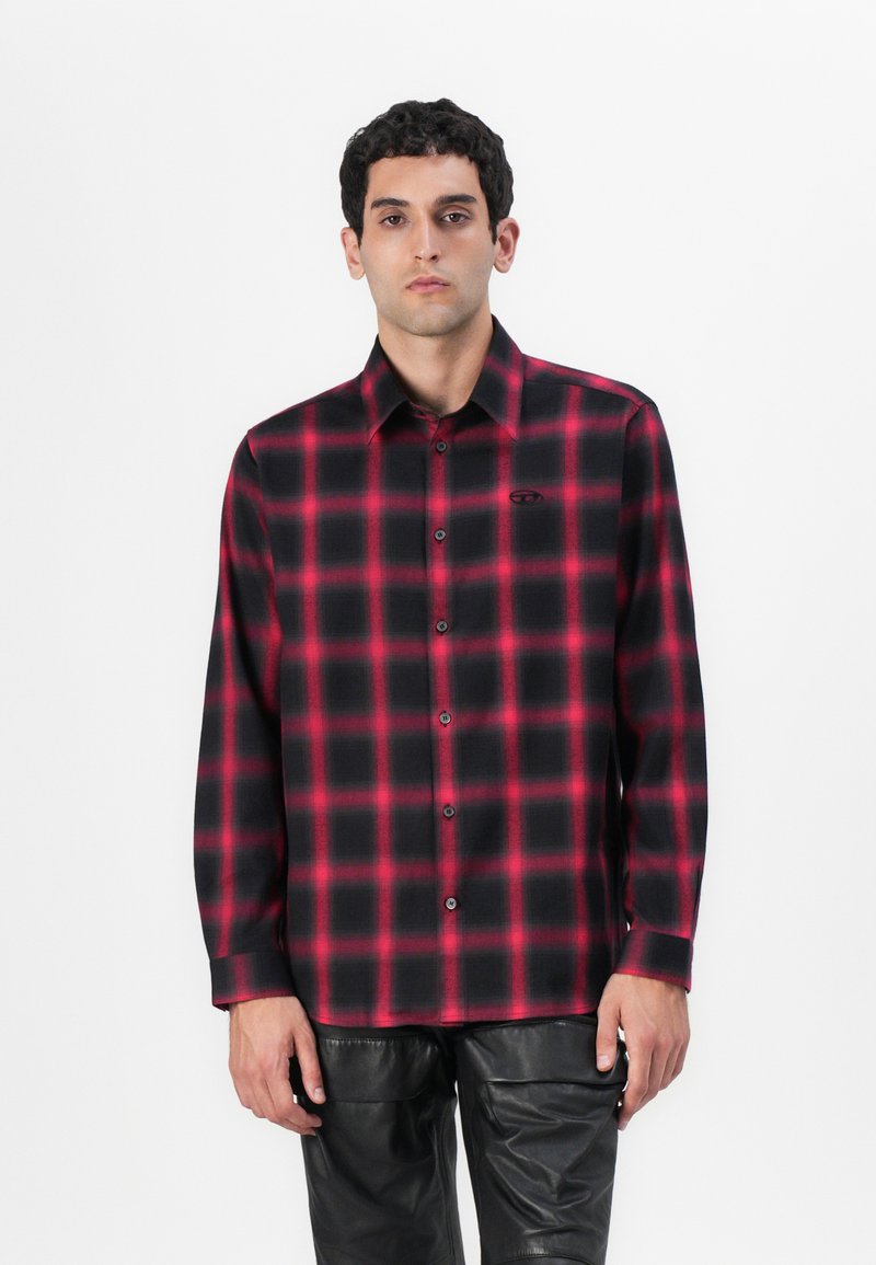 Camisa de cuadros de manga larga para hombre en patrón de cuadros rojos y negros, con cuello button-down y un sutil logo en el pecho.