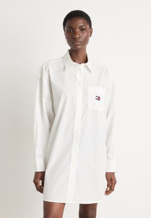 White button-up shirt dress made of cotton, featuring a chest pocket with a logo, long sleeves, and a straight-cut design.