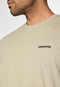 Μαλακό βαμβακερό κοντομάνικο σε ανοιχτό χακί χρώμα. Διαθέτει στρο γγυλή λαιμόκοψη και μικρό μαύρο λογότυπο «patagonia» στην επάνω αριστερή πλευρά. Απαλή υφή.