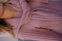 Langärmliger Strickpullover in Hellrosa mit strukturiertem Rippdesign und gedrehten Kragenakzenten, der einen lässigen, geschichteten Look kreiert.