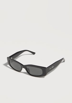 Μαύρα ορθογώνια γυαλιά ηλίου με σκούρους φακούς και χοντρά πλαίσια, γωνιακά για να φαίνεται ο αριστερός βραχίονας με το λευκό λογότυπο "Jimmy Choo".