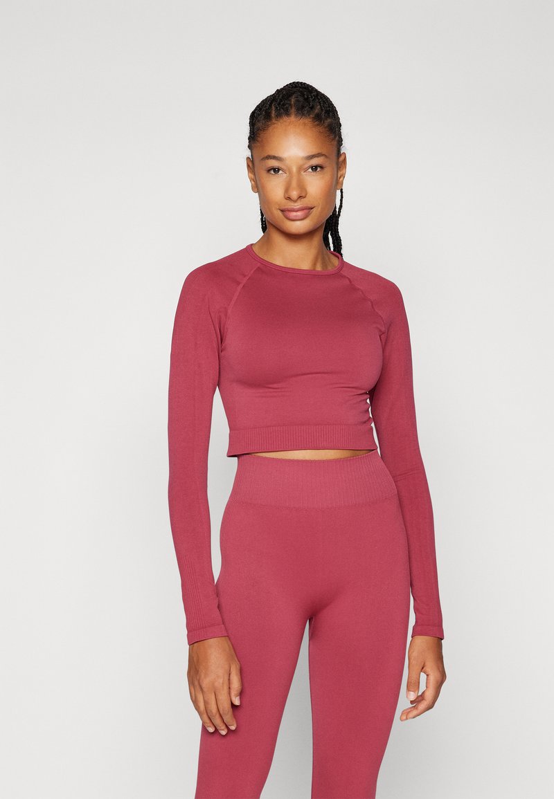 Hosszú ujjú, rövidített felső és magas derekú leggings mauve színben, rugalmas anyagból, bordás részletekkel az ujjakon és a deréknál.