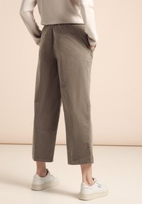 Lichtbruine, cropped broeken met een losse pasvorm en een elastische tailleband. Bevat zijzakken en een gestructureerde stof, gecombineerd met witte sneakers.