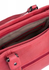 Borsa a tracolla rossa in pelle con una texture liscia, dotata di comparto con zip, tracolla regolabile e rivestimento beige.