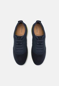 Sneakers blu navy con un mix di materiali scamosciati e tessili. Presentano lacci elastici, una soletta perforata e una suola verde lime in contrasto.