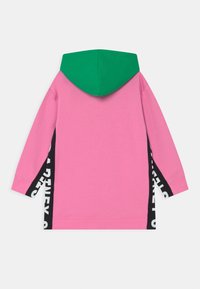 Sudadera de manga larga de color rosa con capucha verde y paneles laterales negros, con gran texto blanco, mostrada desde la parte posterior sobre un fondo blanco.