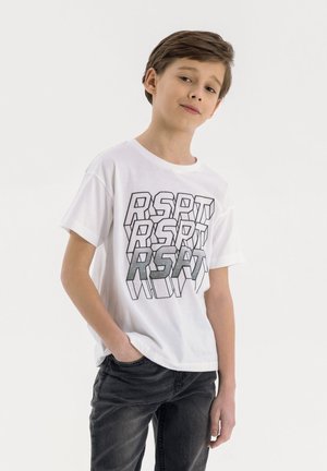 Camiseta de algodón blanca con un atrevido texto gráfico en negro y plateado "RSPT" en un patrón repetido. Mangas cortas, corte relajado. Combinada con jeans gris oscuro.