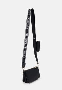 Černá kabelka s texturovaným povrchem, zlatým zipem a odnímatelným popruhem s názvem značky bílým písmem na černém pozadí.