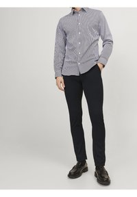 Randig skjorta i marinblått och vitt, med långa ärmar och figursydd design. Kombinerad med svarta slim-fit byxor och svarta loafers.