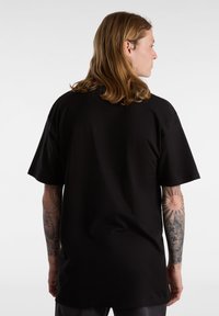 Black oversized t-shirt made of soft cotton, featuring short sleeves and a clean design. The back is plain with no additional patterns or accents.