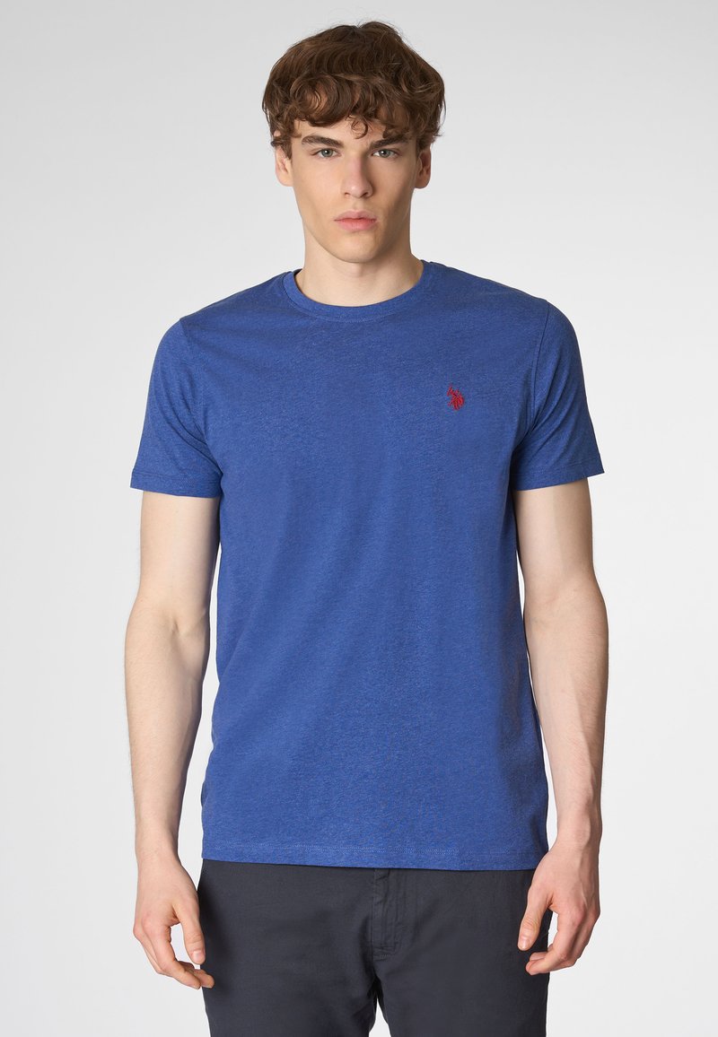 T-shirt blu con collo girocotolo, realizzato in un tessuto testurizzato, dotato di maniche corte e un piccolo logo rosso sull'area sinistra del petto.