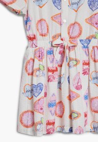 Abito in tessuto leggero e texturizzato con un motivo colorato di cuori e forme nei toni di rosa, arancione e blu, con vita legata e chiusura a bottoni.